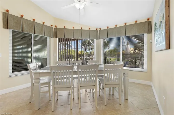 Dining room with light tile patterned flooring, lofted ceiling, and a ceiling fan