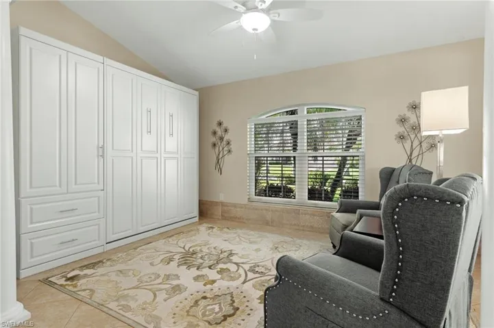 Sitting room with light tile patterned flooring, lofted ceiling, and a ceiling fan