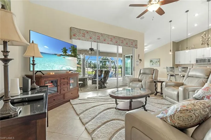 Living area with a ceiling fan, light tile patterned floors, high vaulted ceiling, and a sunroom
