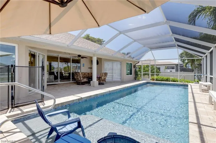 Outdoor pool with a sunroom, a patio, glass enclosure, and a ceiling fan