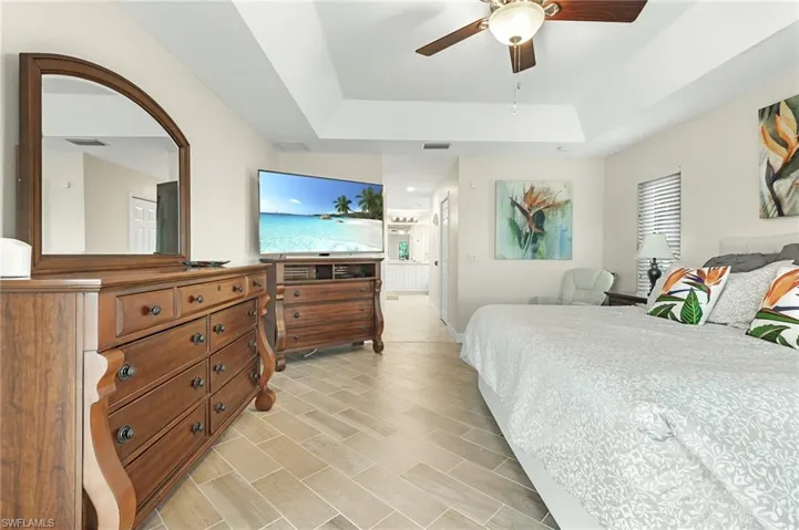 Bedroom with a ceiling fan, wood tiled floors, and a raised ceiling