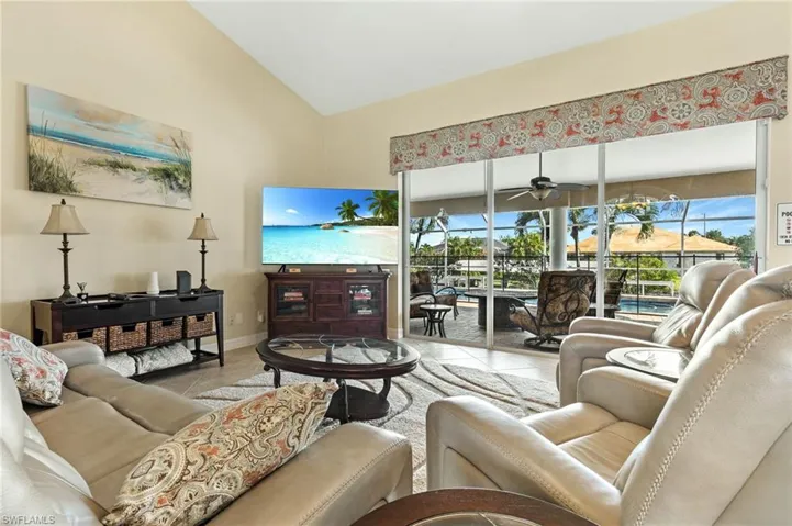 Living area featuring tile patterned floors, high vaulted ceiling, a sunroom, and a ceiling fan