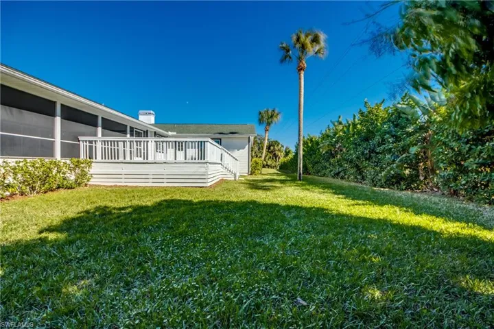 View of grassy yard with a wooden deck