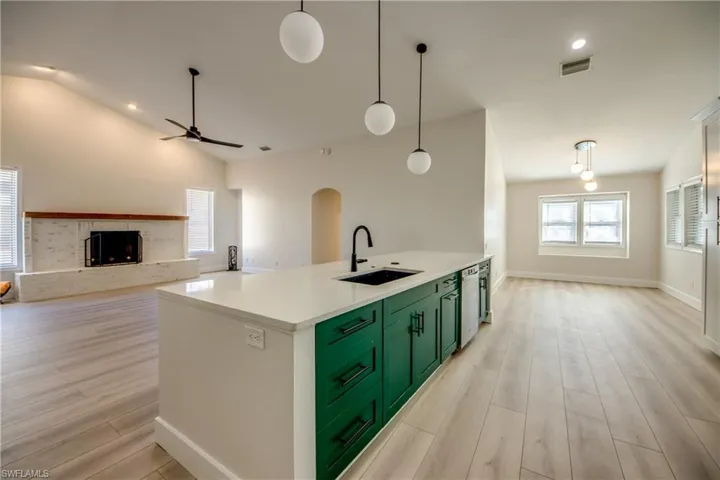 Kitchen featuring green cabinetry, open floor plan, recessed lighting, light wood-style floors, and hanging light fixtures