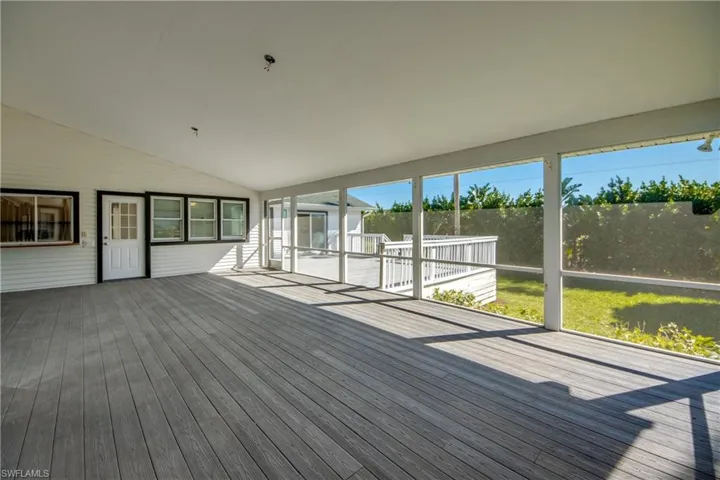 Unfurnished sunroom with vaulted ceiling and a deck