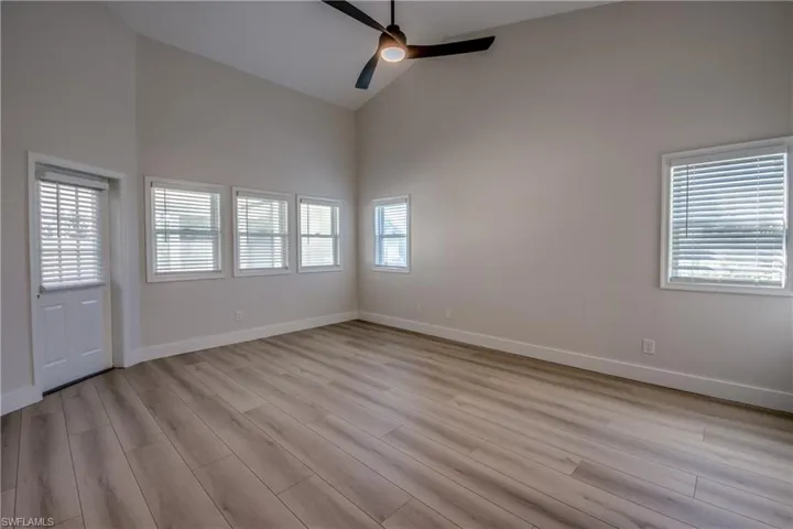 Empty room featuring high vaulted ceiling, a ceiling fan, and light wood finished floors