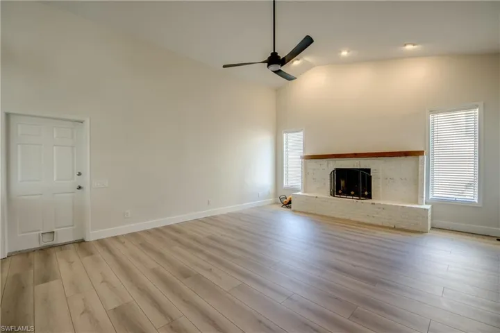 Unfurnished living room featuring high vaulted ceiling, a fireplace, light wood finished floors, a ceiling fan, and recessed lighting