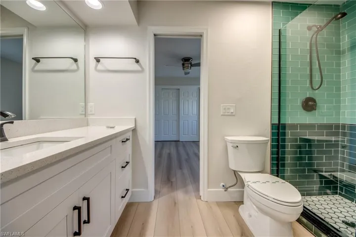 Full bathroom with a tile shower, vanity, and light wood finished floors