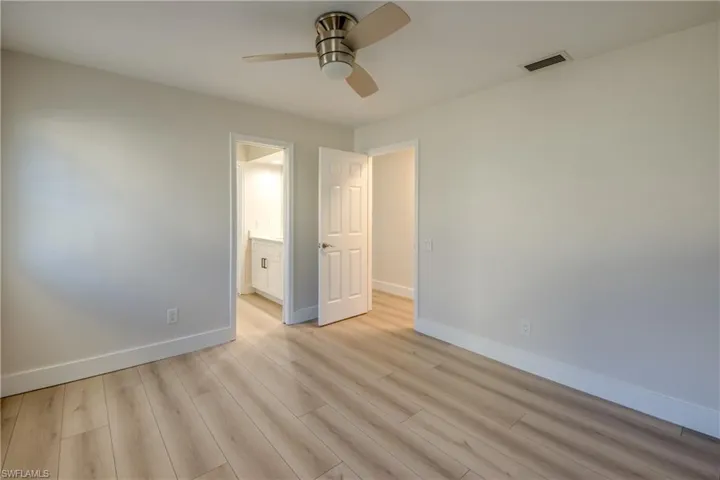 Unfurnished bedroom with light wood-style floors, a ceiling fan, and ensuite bathroom