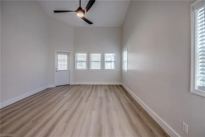 Spare room with a high ceiling, light wood-style flooring, plenty of natural light, and ceiling fan
