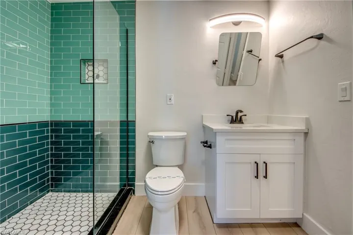 Full bathroom with a stall shower, vanity, and light wood-style floors