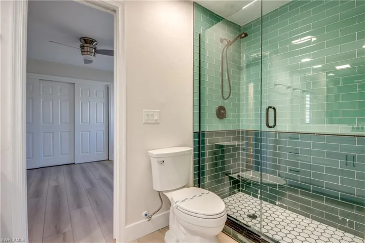 Full bath with a shower stall, wood finished floors, and a ceiling fan