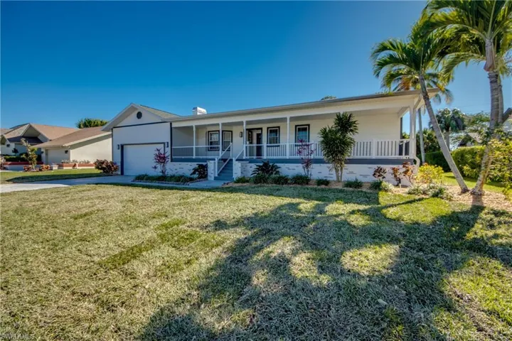 View of front of property featuring a porch, a front yard, a chimney, a garage, and driveway
