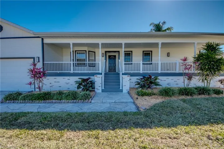 View of front facade featuring covered porch, a front lawn, and a garage