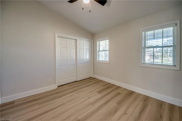 Unfurnished bedroom featuring vaulted ceiling, light wood-type flooring, a closet, and a ceiling fan