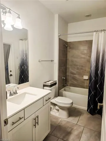 Bathroom featuring vanity, toilet, shower / tub combo, and tile patterned flooring