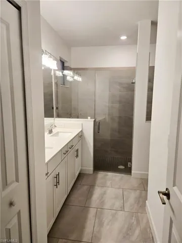 Bathroom featuring vanity, a stall shower, and baseboards