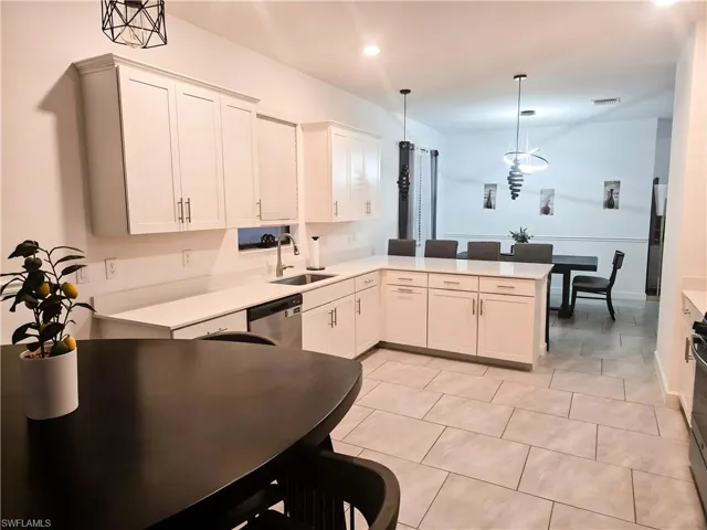 Kitchen featuring a sink, stainless steel dishwasher, hanging light fixtures, light countertops, and recessed lighting