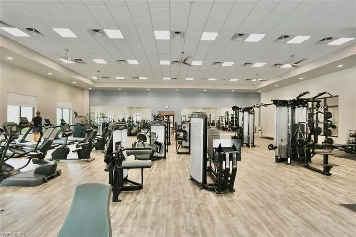 Workout area featuring light wood-style floors, a high ceiling, and a drop ceiling