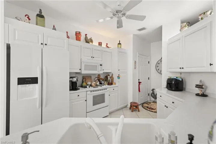 Kitchen with white appliances, white cabinets, and light countertops