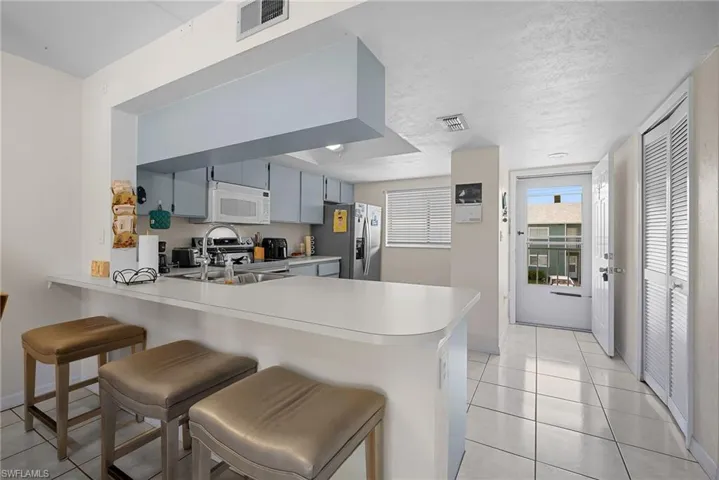 Kitchen featuring a peninsula, light countertops, light tile patterned floors, a breakfast bar area, and stainless steel appliances