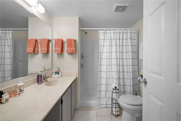 Bathroom with light tile patterned flooring, a stall shower, and vanity