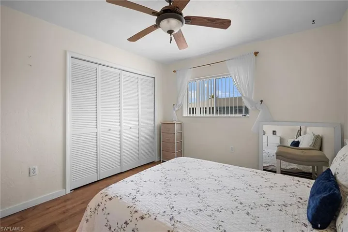 Bedroom with dark wood-style floors, a ceiling fan, and a closet