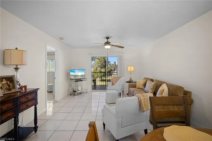 Tiled living room with a ceiling fan and baseboards