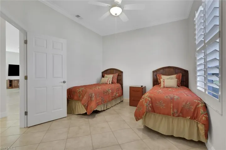 Tiled bedroom featuring ornamental molding and a ceiling fan