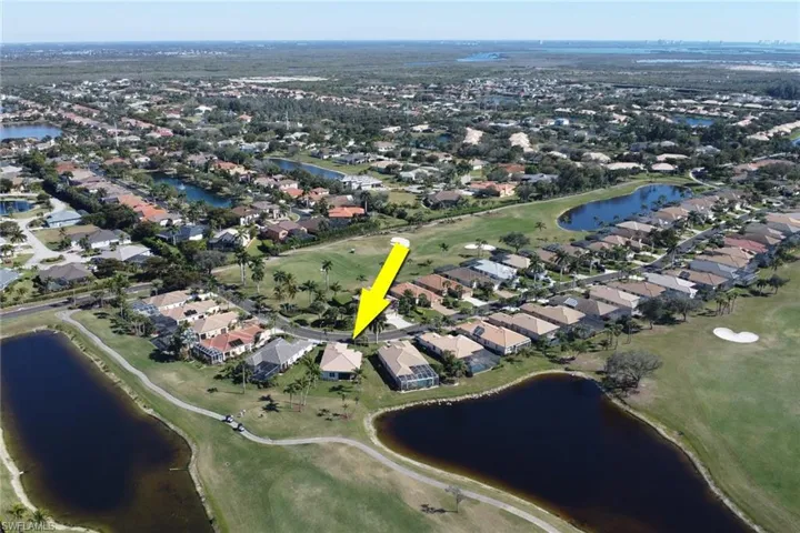 Aerial view of property and surrounding area with nearby suburban area, a local golf course, and a large body of water
