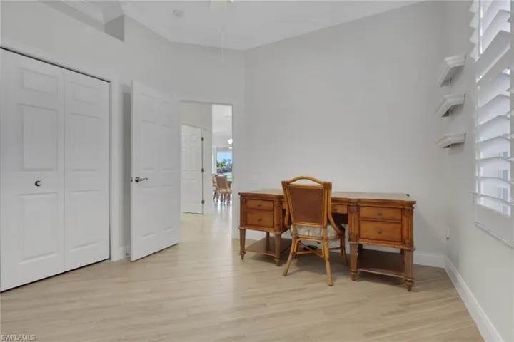 Office with light wood-style floors, crown molding, and a high ceiling