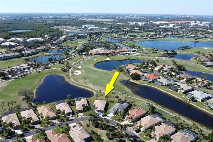 Aerial view of property's location with a golf course and nearby suburban area