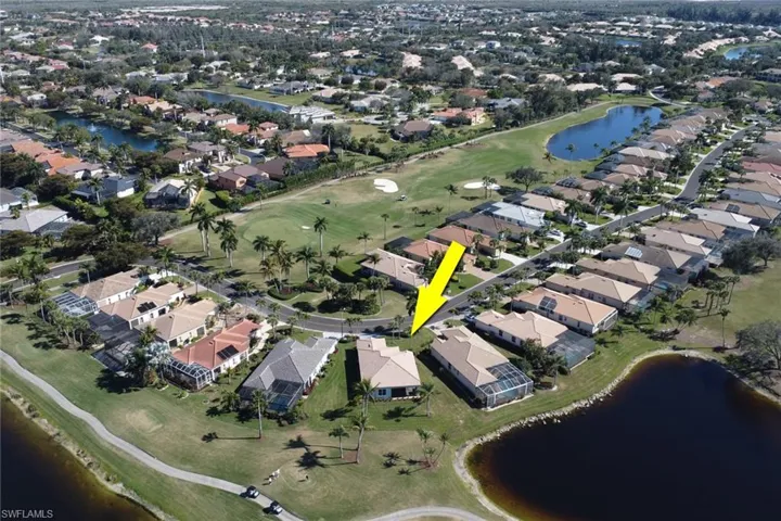Aerial view of property's location featuring a large body of water, a golf club, and nearby suburban area