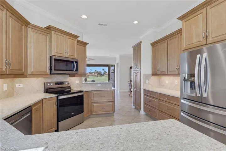 Kitchen with stainless steel appliances, light stone countertops, light tile patterned floors, recessed lighting, and crown molding