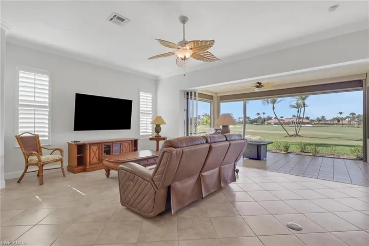 Living room featuring a ceiling fan, light tile patterned flooring, and crown molding