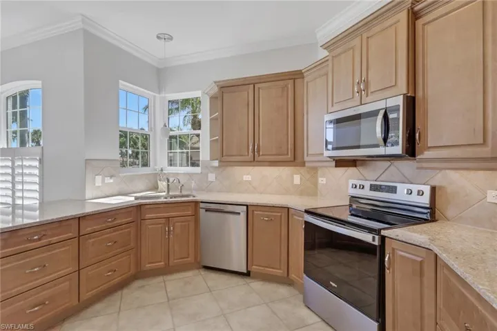 Kitchen with stainless steel appliances, light stone countertops, open shelves, ornamental molding, and light tile patterned floors