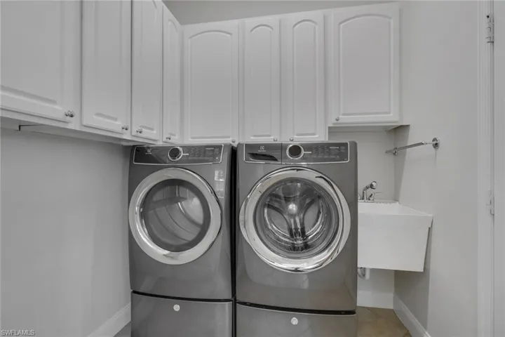 Laundry room with cabinet space, independent washer and dryer, and light tile patterned floors