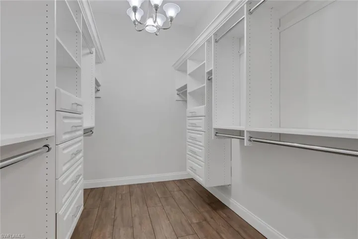 Walk in closet with a chandelier and light wood-type flooring