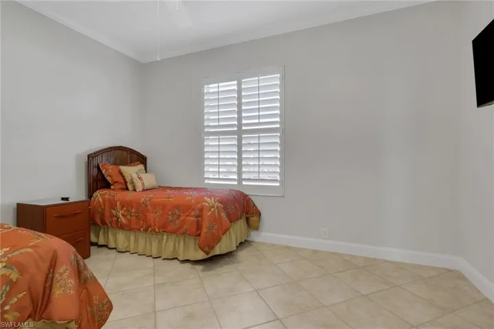 Bedroom with crown molding, a ceiling fan, and light tile patterned floors
