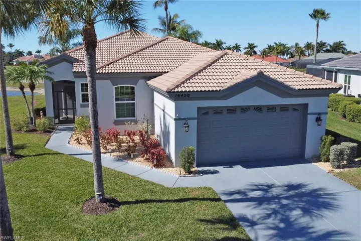 View of front facade featuring a front yard, stucco siding, a garage, concrete driveway, and a tiled roof