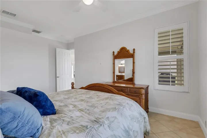Bedroom with crown molding, light tile patterned floors, and ceiling fan