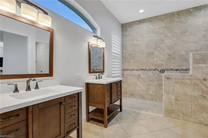 Full bathroom featuring two vanities, a walk in shower, recessed lighting, and light tile patterned flooring