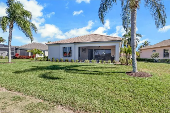 Back of house featuring a yard, a tiled roof, stucco siding, and a sunroom