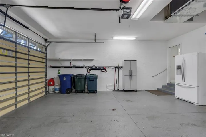 Garage with white fridge with ice dispenser, a textured wall, and a garage door opener
