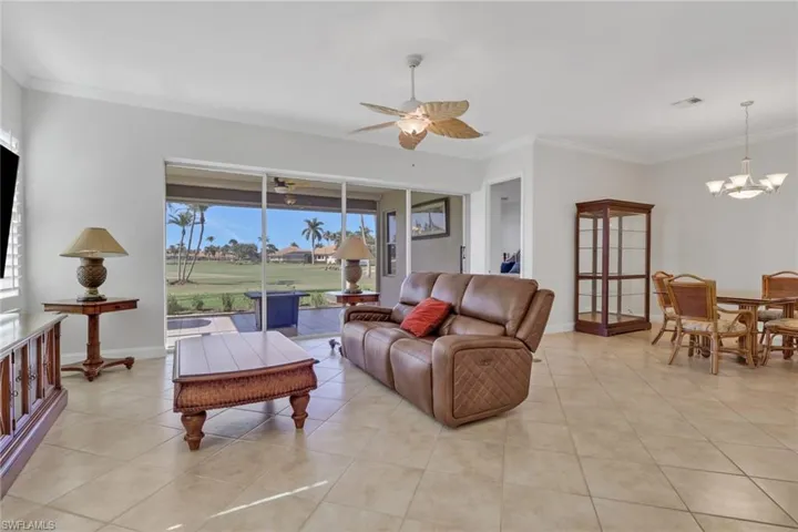 Living area featuring crown molding, ceiling fan, light tile patterned floors, and a chandelier