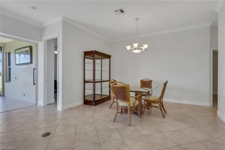 Dining space with ornamental molding, light tile patterned floors, and suspended lighting