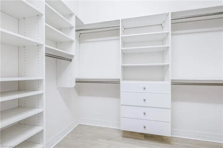 Walk in closet with light hardwood / wood-style floors