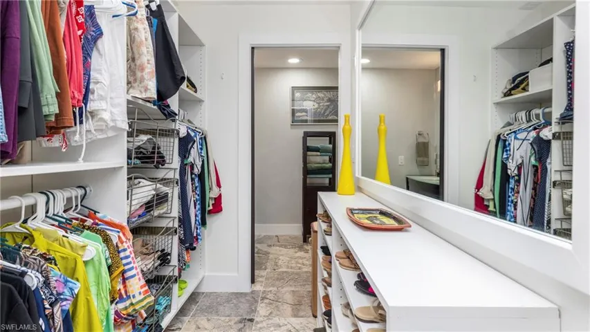 Walk in closet with light stone finish floors