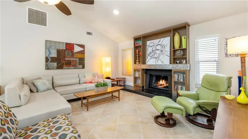 Living area with lofted ceiling, ceiling fan, a premium fireplace, light tile patterned floors, and recessed lighting