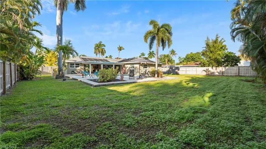 Rear view of house featuring a fenced backyard, a patio area, and roof mounted solar panels
